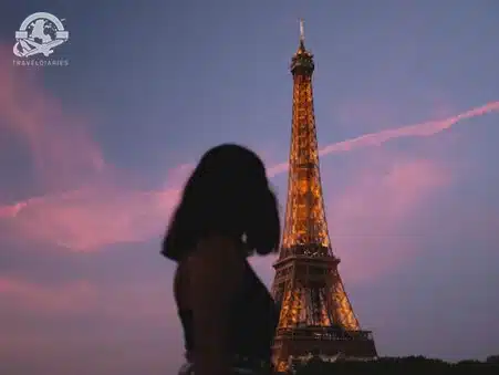 Girl standing near Eiffel tower during night time; Paris, France